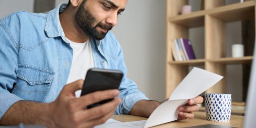 Young,Indian,Businessman,Holding,Phone,Reading,Bank,Receipt,Calculating,Taxes,