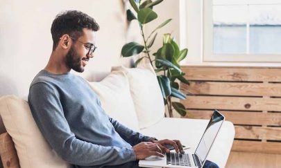 Handsome young man using laptop computer at home. Student men resting  in his room. Online shopping, home work, freelance, online learning, studying concept. Distance education